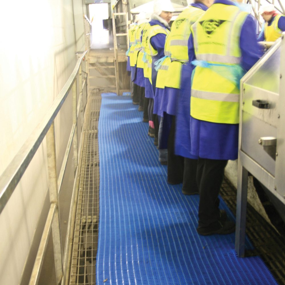 Workers-standing-in-a-line-together- on-a-blue-anti-fatigue-COBAmat- heavy