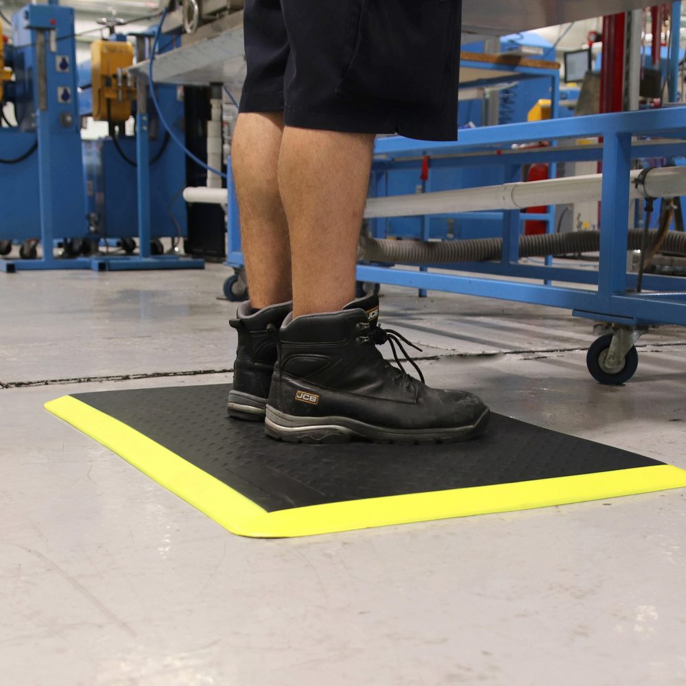 Person-standing-next-to-work-station- on-a-black/yellow-COBAelite-diamond- mat