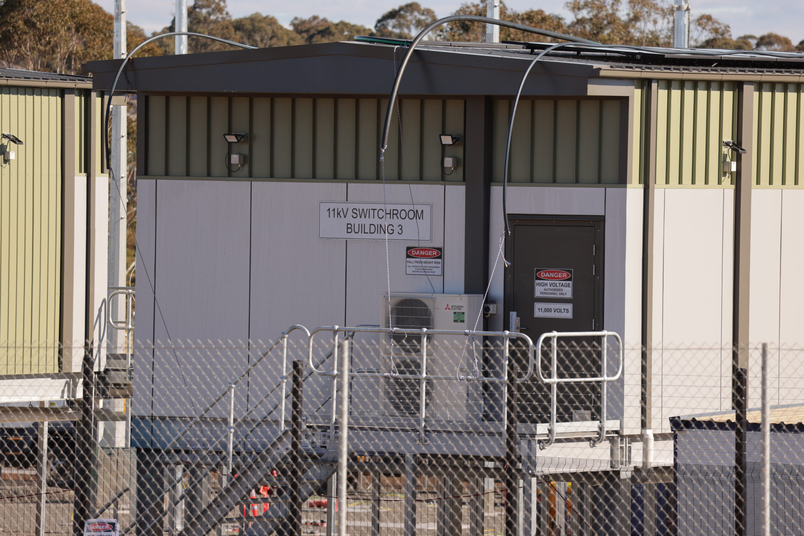 Exterior of an 11kV switchroom with high-voltage warning signs and restricted access fencing.
