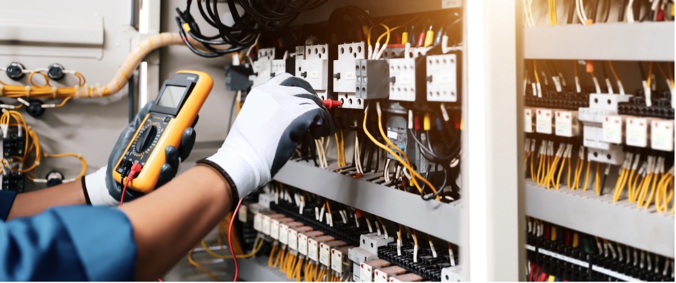 Technician working at an electrical control panel with electrical insulating matting positioned in front of the equipment.